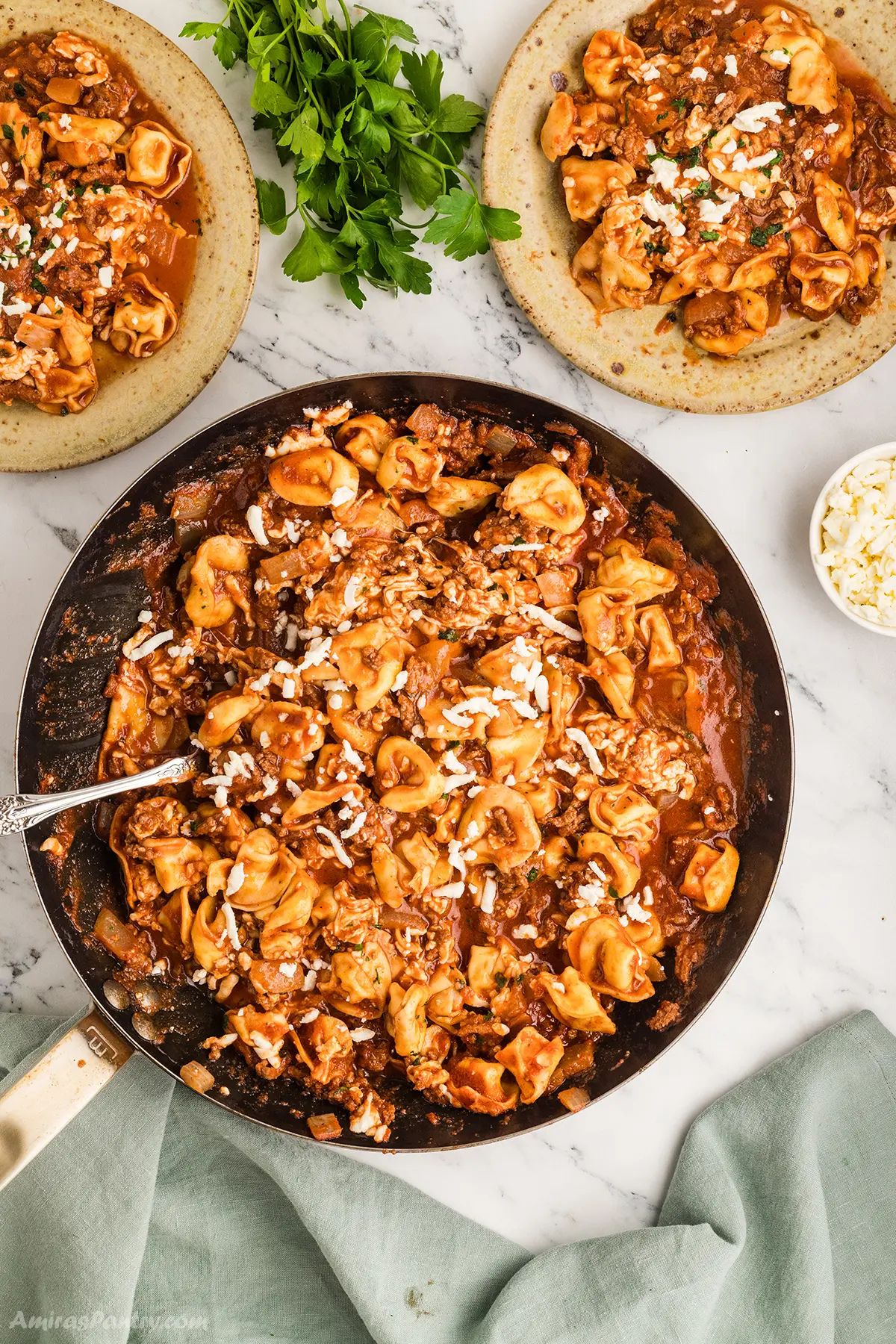 An overhead image of a skillet with tortellini ground beef.