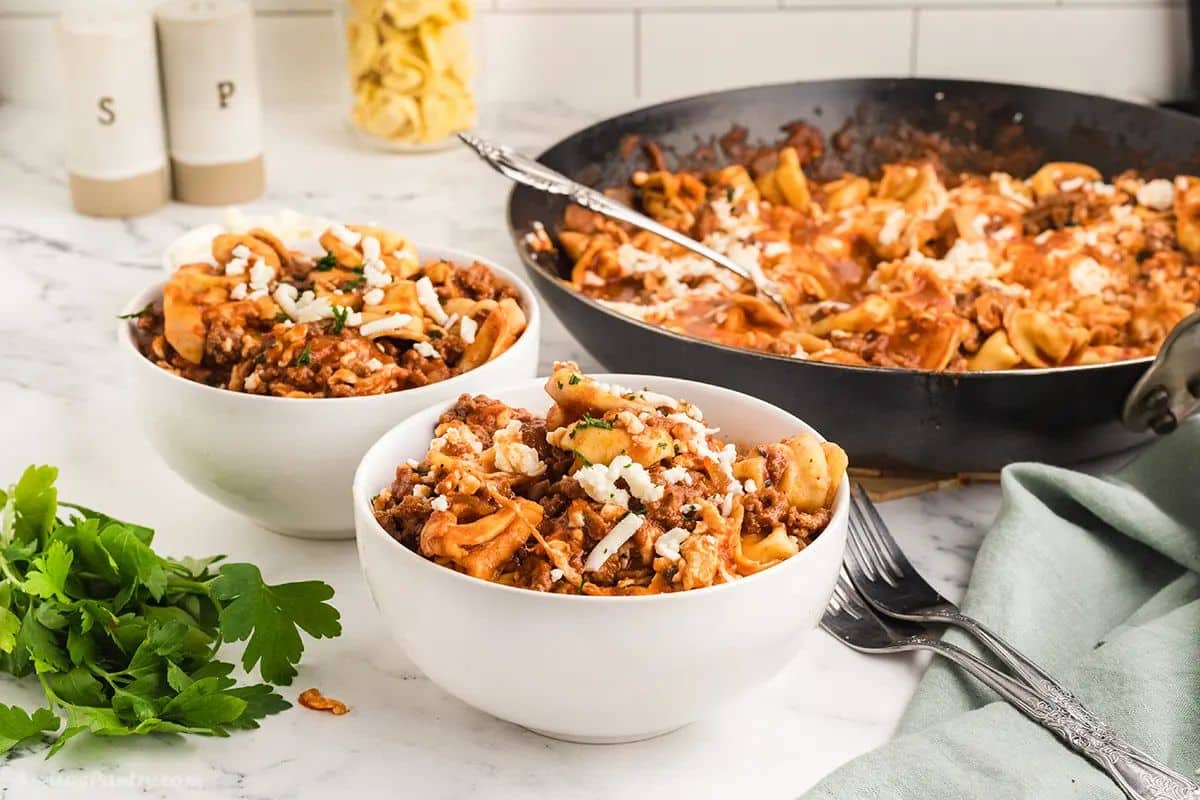 Two white bowl with tortellini ground beef dinner.