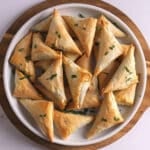 An overhead image of Spanakopita triangles on a white platter.