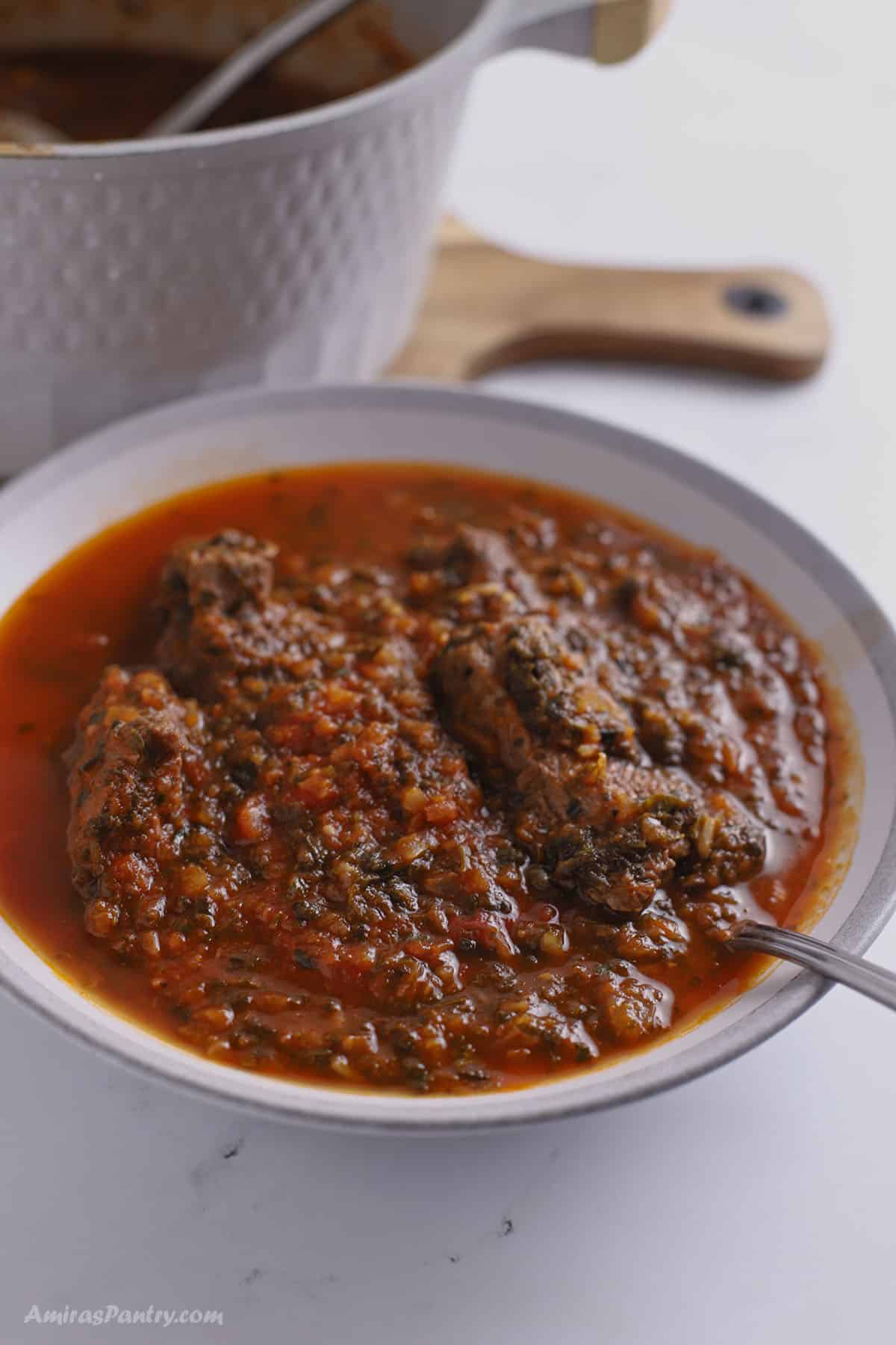 Spinach in tomato based sauce on a large bowl with a spoon.