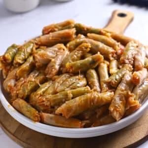 A side image of a plate with cabbage rolls on a wooden board.