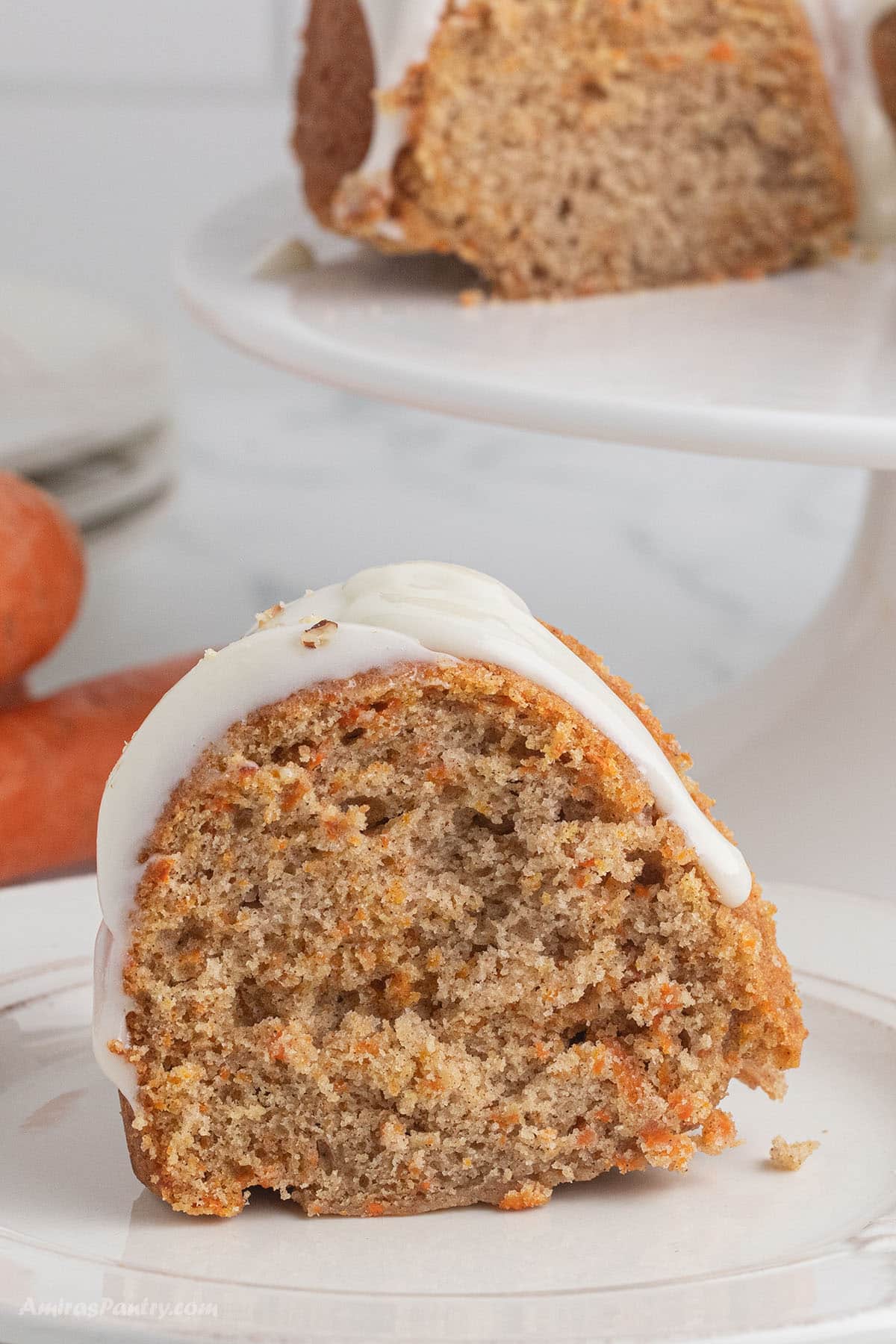 A close up image on a slice of carrot bundt cake on a white plate.