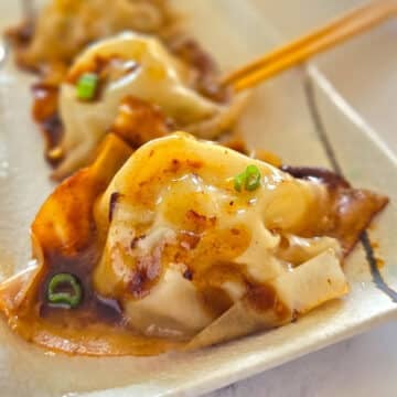 A close up image on a dumpling on a white plate.