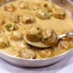 Chicken Swedish meatballs in a stainless steal skillet garnished with parsley.