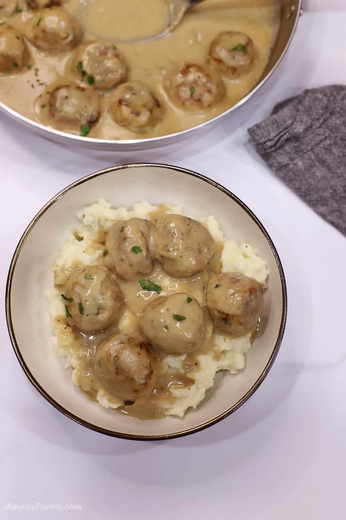 An overhead image of a dinner plate with mashed potatoes topped with chicken Swedish meatballs.