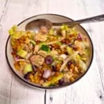 A metal spoon on a bowl of crispy pasta salad.