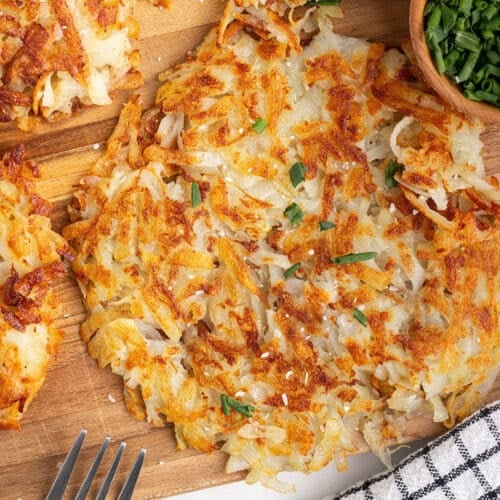 A potato roasti on a wooden board garnished with salt flakes.