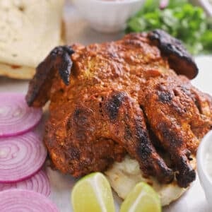 Tandoori whole chicken with lime wedges.