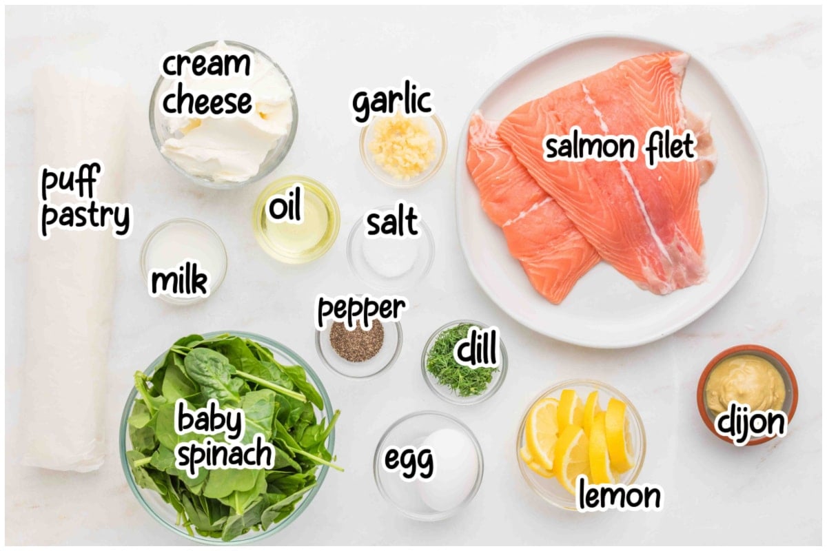 Flat lay of ingredients for a salmon puff pastry recipe on a light marble surface.
