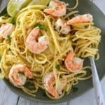 A Serving of shrimp scampi on a green plate with a fork.
