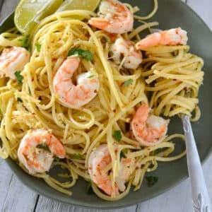 A Serving of shrimp scampi on a green plate with a fork.