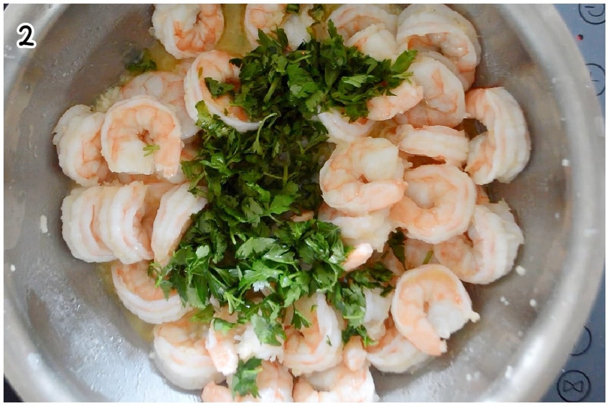 A large pot with cooked shrimp topped with chopped parsley.