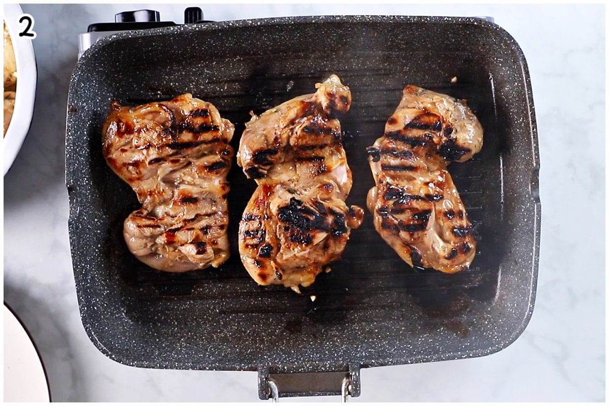 A grilling pan with balsamic chicken thighs being grilled.