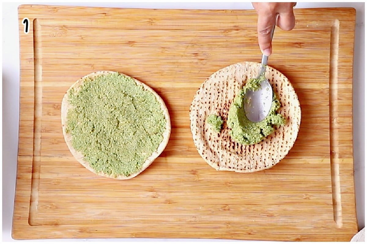 Spreading raw falafel batter onto a small pita on a wooden cutting board.
