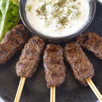 An overhead image of kofta on a black platter.