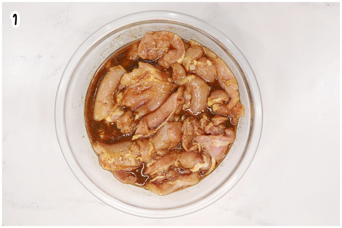 Raw chicken thighs marinating in a glass bowl with soy sauce, honey, and spice marinade.