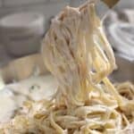 Pinterest pin for Alfredo Sauce with Half and Half, showing tongs lifting creamy fettuccine noodles from a skillet.