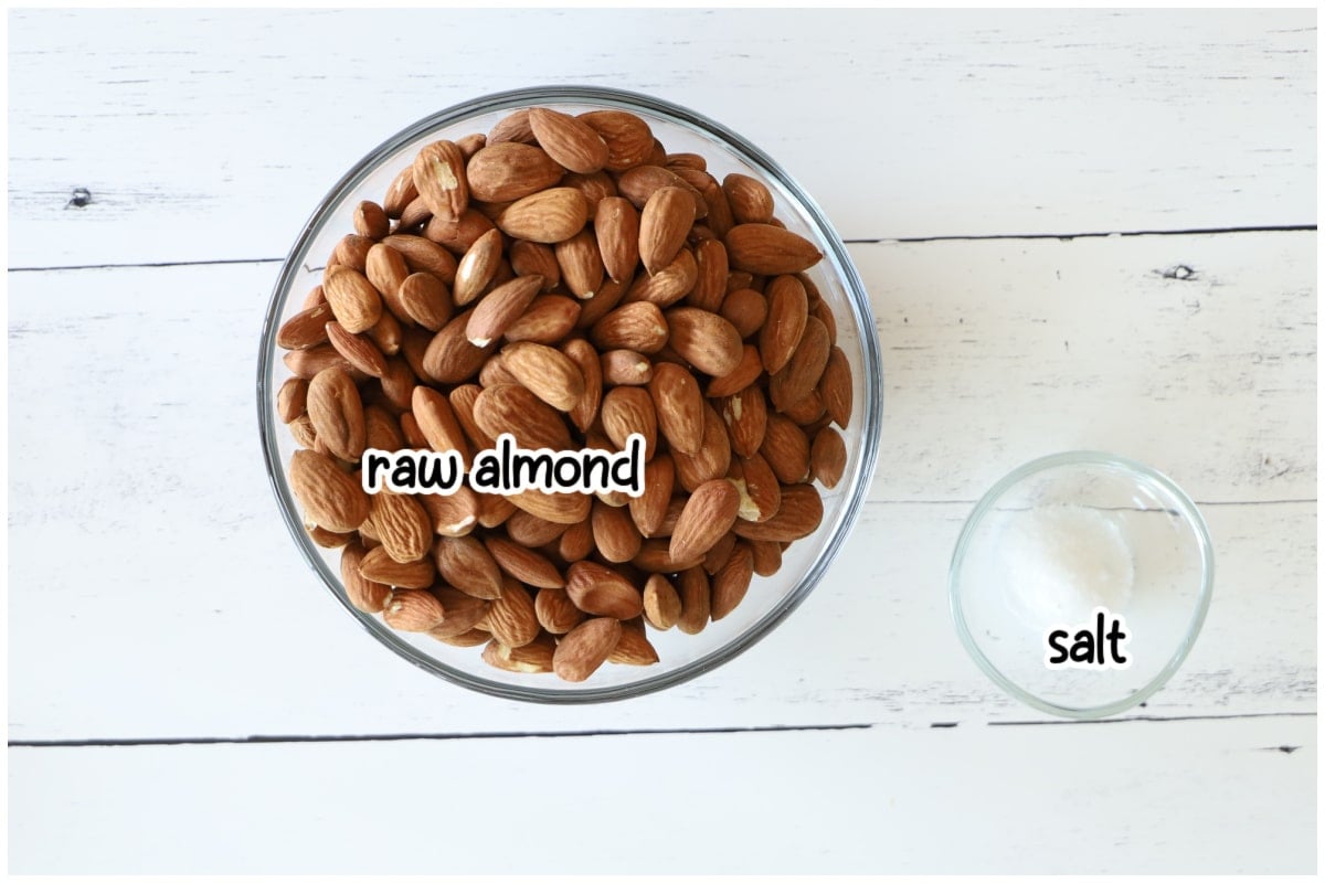 Overhead flat lay of almond butter ingredients on a white wooden surface.