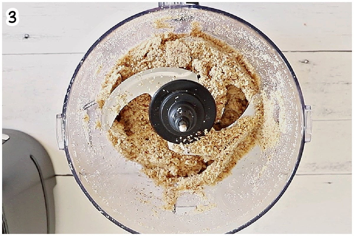 Almonds forming a clumpy dough-like consistency in a food processor.