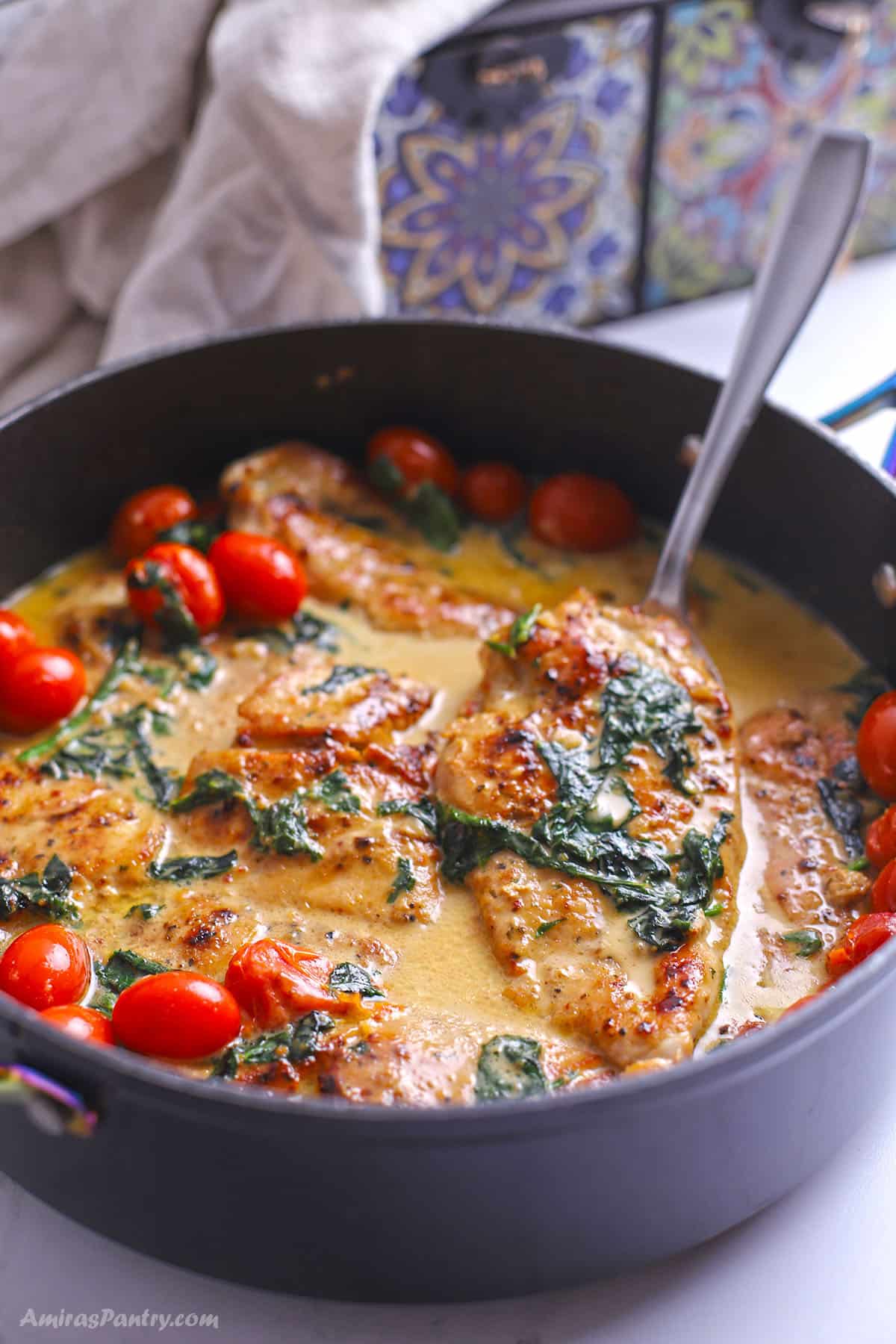 A large skillet with creamy Italian chicken garnished with tomatoes.