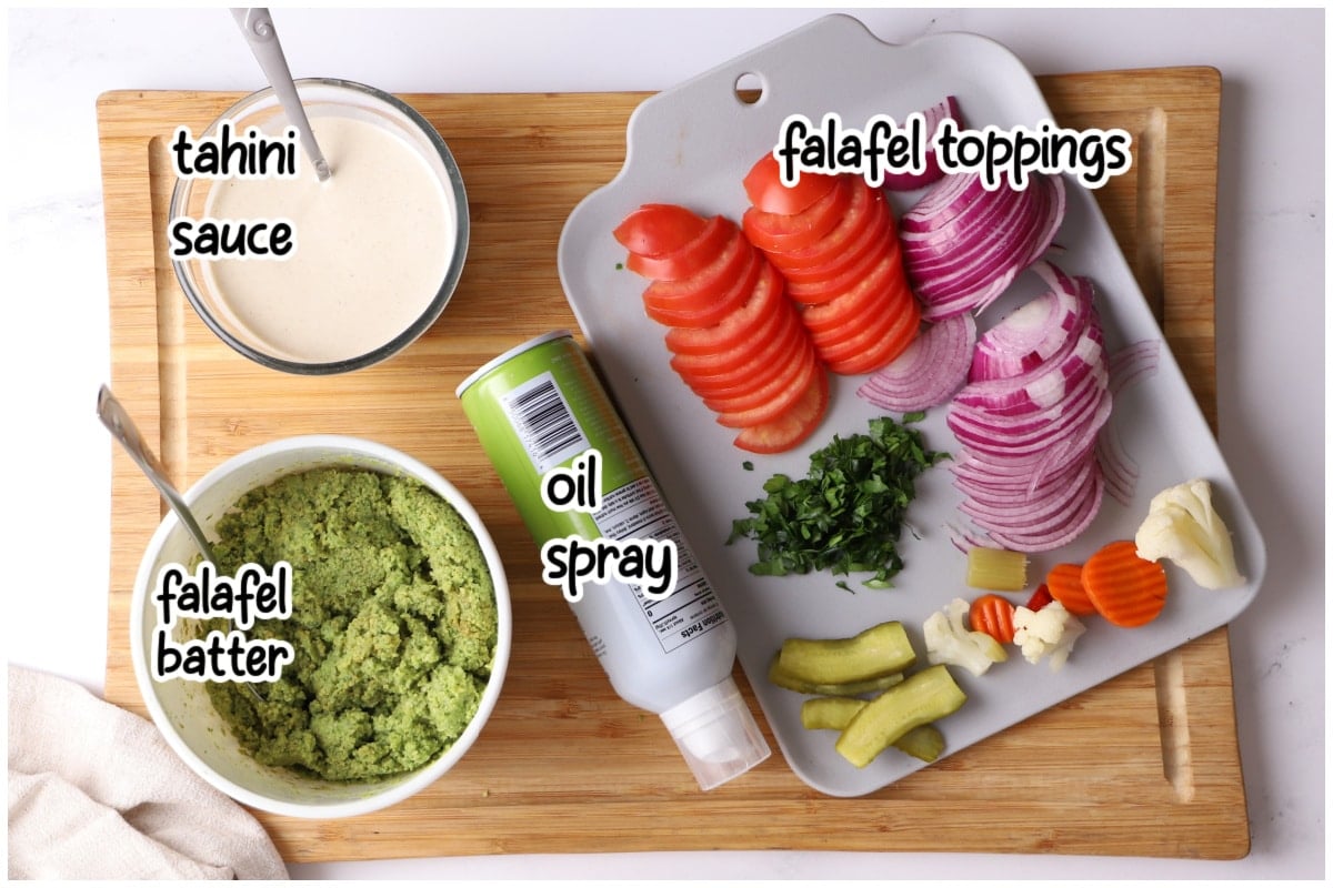 Overhead flat lay of falafel waffle ingredients on a wooden board with text overlay.