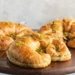 A close up image on a pistachio croissant on a wooden board.