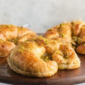 A close up image on a pistachio croissant on a wooden board.