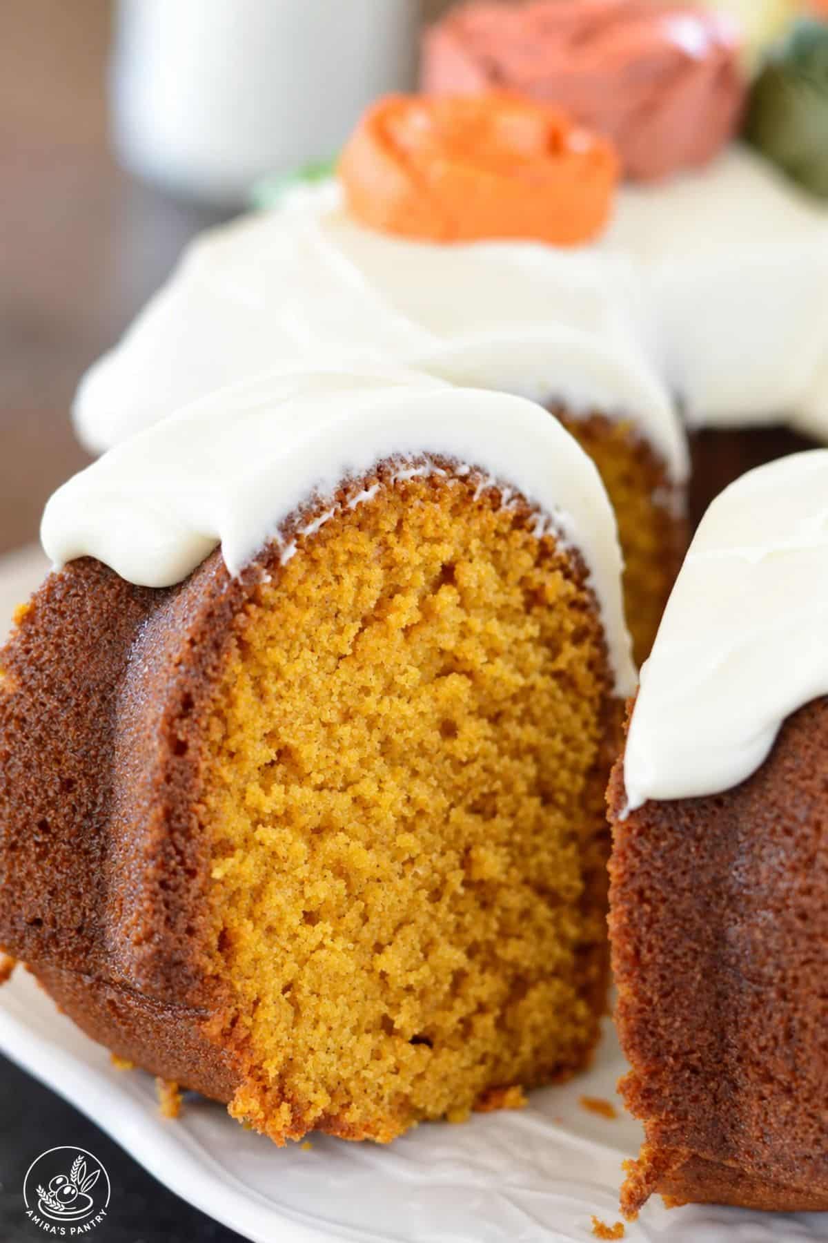 Slice of frosted pumpkin bundt cake with cream cheese icing decorative frosting roses.
